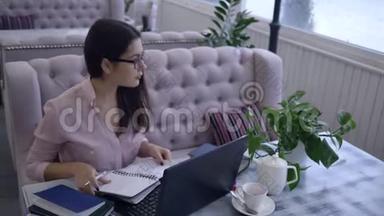 远程学习，女学生用钢笔在<strong>笔记</strong>本上写<strong>笔记</strong>，坐在书桌上，<strong>笔记</strong>本电脑在室内